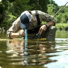 A fisherman drinking from the river.