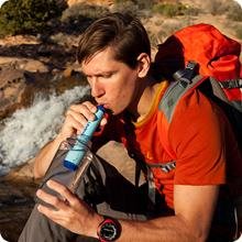 A hiker drinking from a bottle with the LifeStraw.