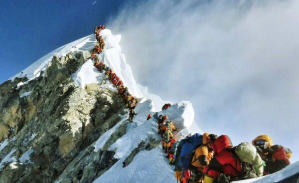 A long line of tourists and their porters (sherpas) waiting to make a trophy photo-session on the Mt Everest.